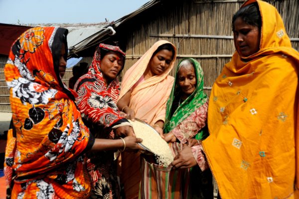 Women pouring grain in to a sack.