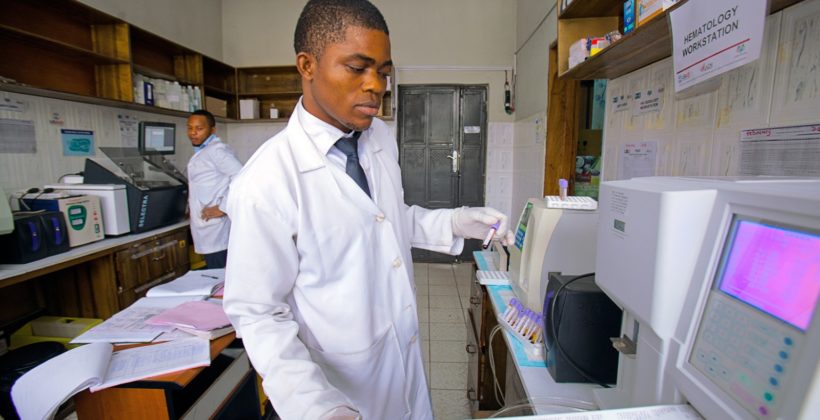 Nigerian lab technician checking test results.